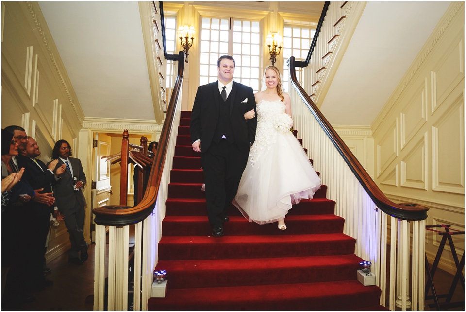 Bride and Groom walk down a red staircase to enter reception at Allerton Park Mansion.