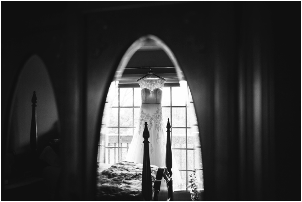 Black and white photo of wedding dress hanging in mirror.