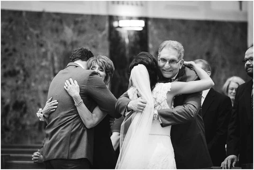 cathedral wedding photography, Bride and groom hug parents during sign of peace.