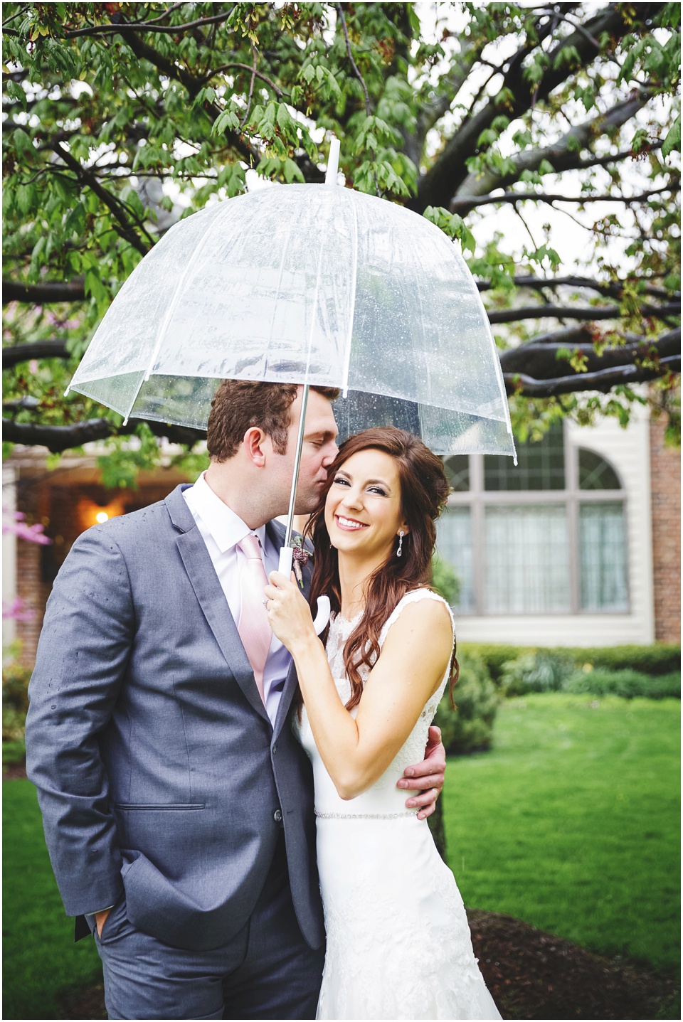cathedral wedding photography, Groom kisses bride under umbrella.
