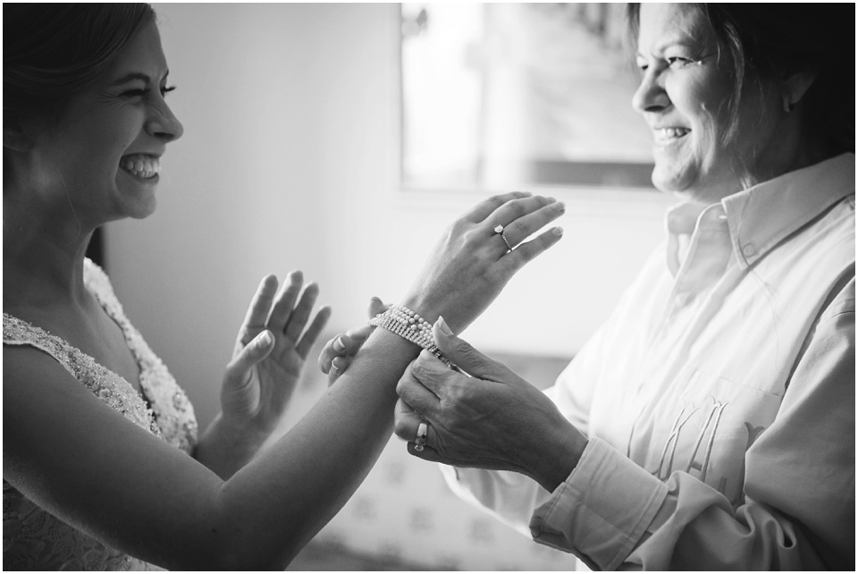 Mother of the bride helps daughter put on jewelry by Central Illinois Wedding Photographer Rachael Schirano