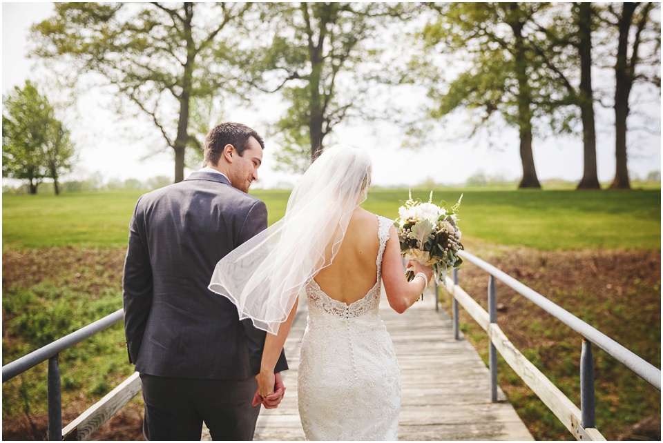 Bride and groom walk across bridge at Kickapoo Creek Winery by Wedding Photographer Rachael Schirano