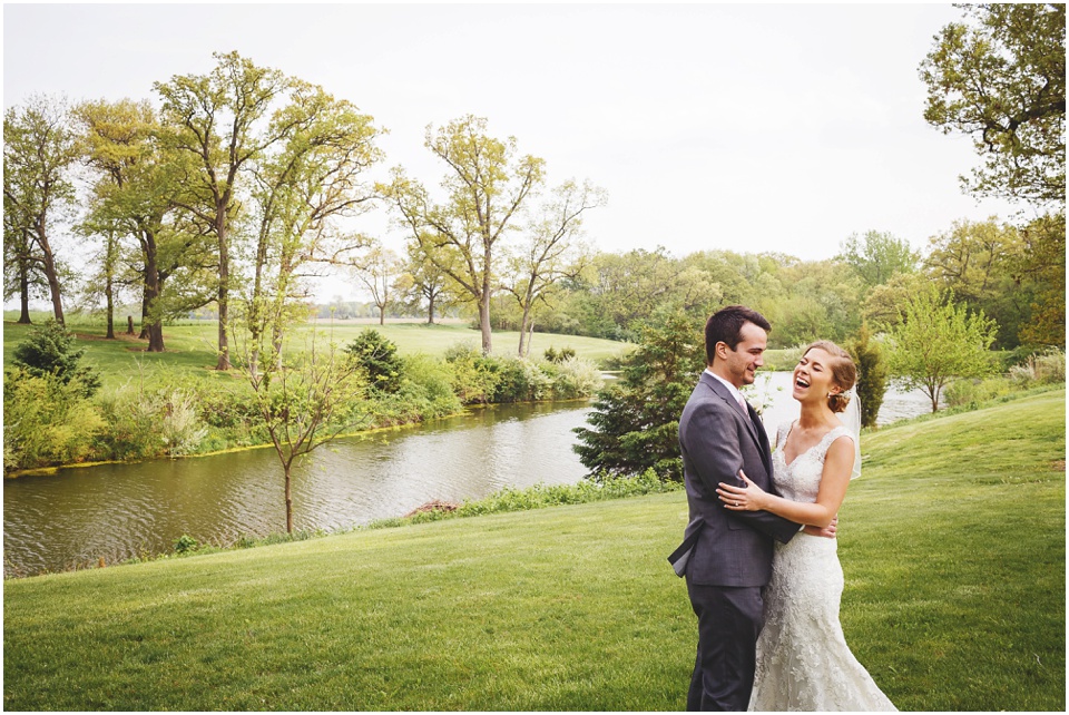 Bride and groom laughing by the lake at Kickapoo Creek Winery by Wedding Photographer Rachael Schirano