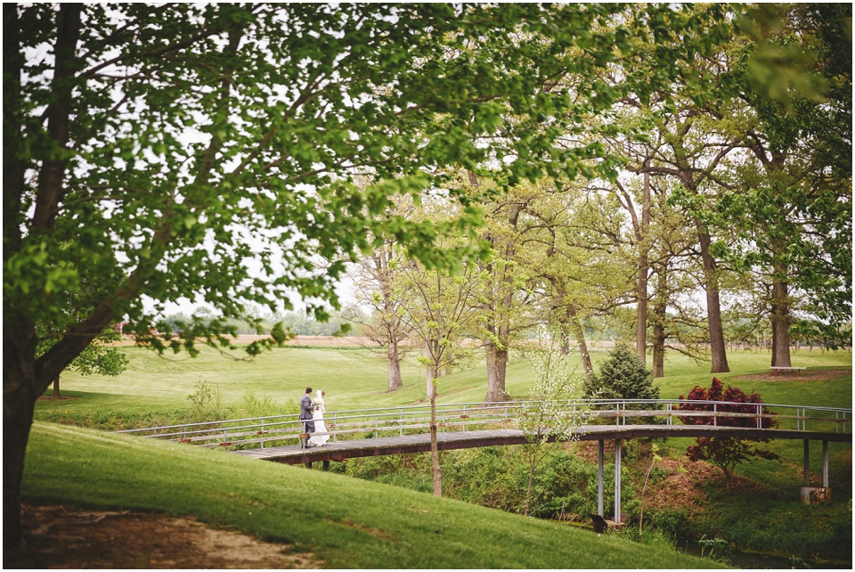 Bride and groom walk across the bridge at Kickapoo Creek Winery by Wedding Photographer Rachael Schirano