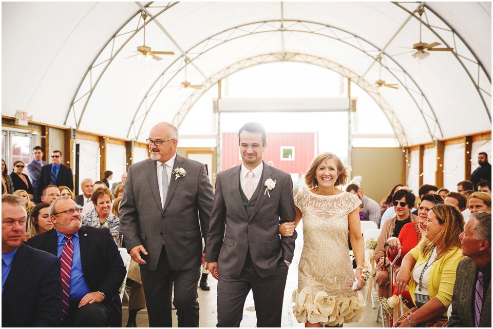 Groom is walked down the aisle by mom and dad at Kickapoo Creek Winery Pavillion Wedding Ceremony by Wedding Photographer Rachael Schirano