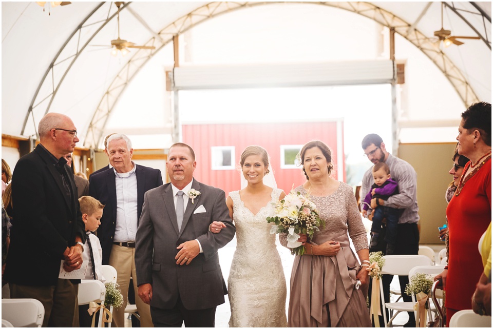 Bride is walked down the aisle by Mom and Dad at Kickapoo Creek Winery Pavillion Wedding Ceremony by Wedding Photographer Rachael Schirano