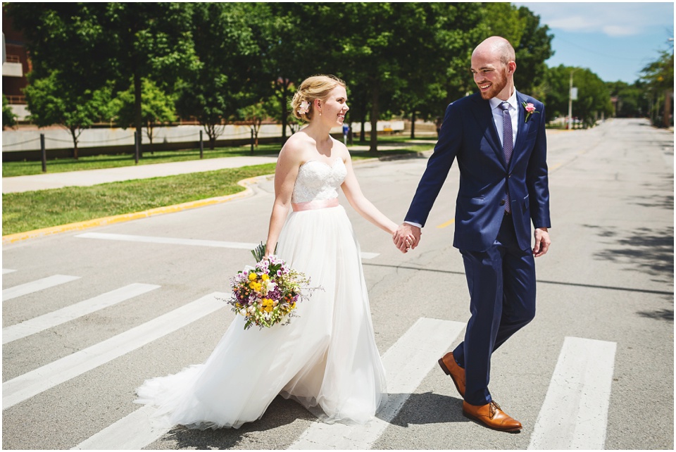 Bride and groom hold hands and walk across the street