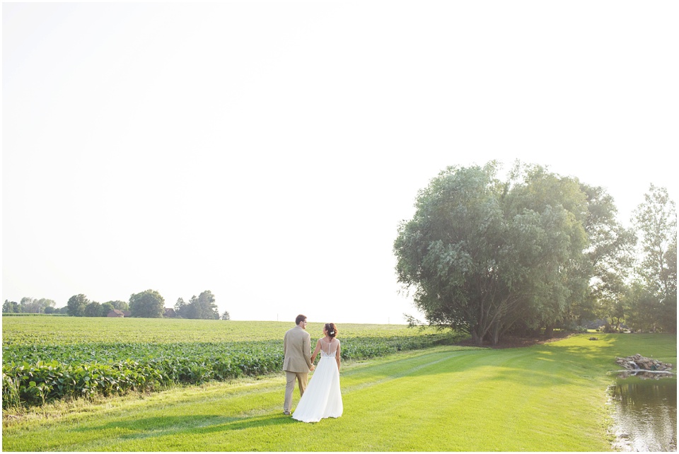 pear tree estates wedding photography, Bride and groom walking through a field.
