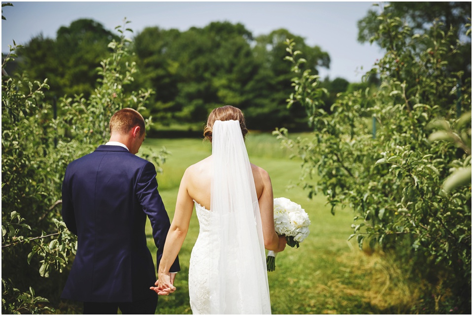 outdoor wedding photography, Bride and Groom walking through field by Bloomington Illinois Wedding Photographer Rachael Schirano
