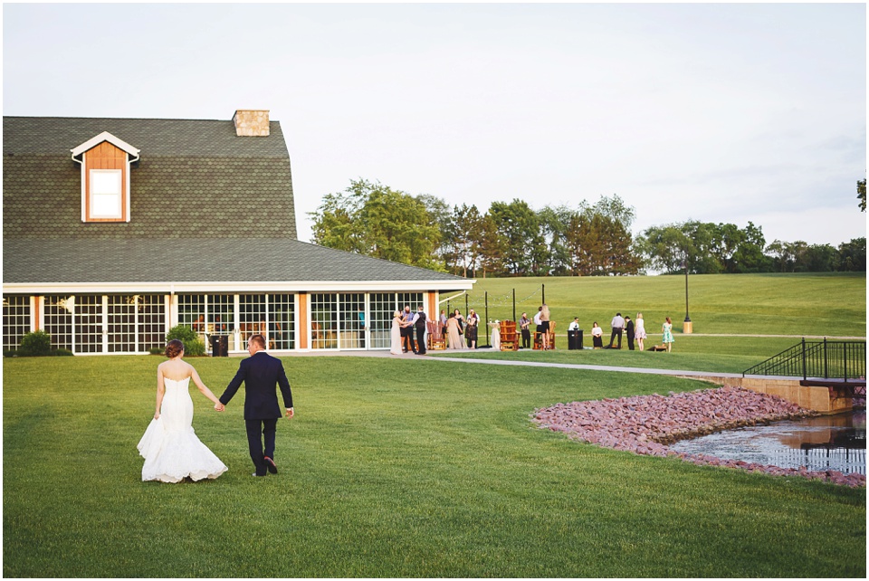 outdoor wedding photography, Bride and groom walk into barn reception by Bloomington Illinois Wedding Photographer Rachael Schirano