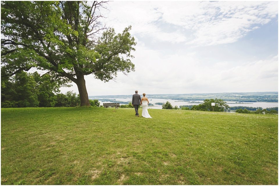 bride and groom walking through a grassy meadow