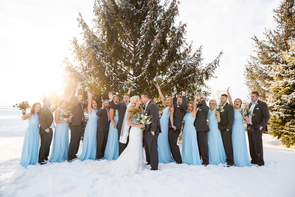 bright blue bridesmaid dresses and black suits in snowy winter wedding portraits