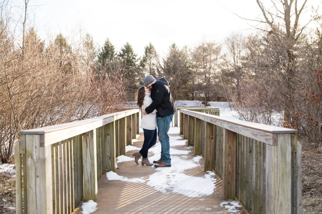 Bloomington IL winter engagement session, Central Illinois engagement photographer, winter engagement, snowy engagement photos, what to wear for a winter engagement, pine tree engagement photos, couple's portraits, engaged couple on a wooden bridge